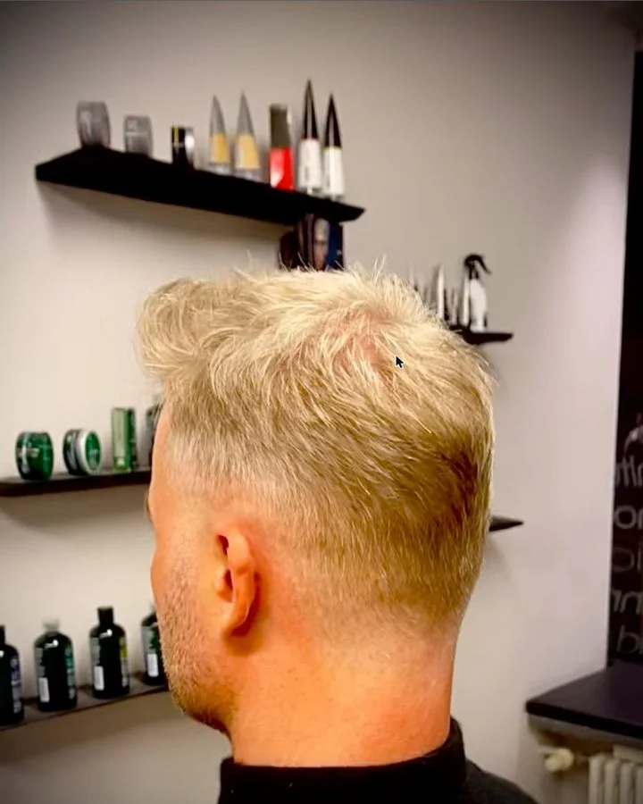 Herrenhaarschnitt von hinten mit Produktregal im Salon