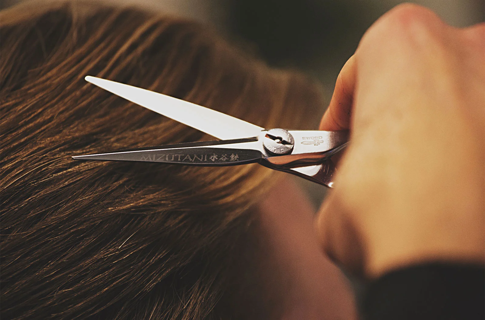 Nahaufnahme einer Friseurschere beim Haarschnitt